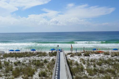 a boardwalk leading to the beach with umbrellas at The Pensacola Beach Resort in Pensacola Beach