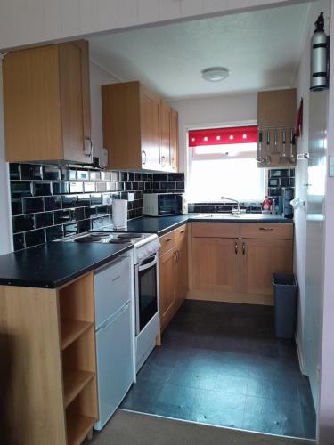 a kitchen with wooden cabinets and a white stove top oven at alicias chalets ,free WIFI & swimming pool passes in Great Yarmouth