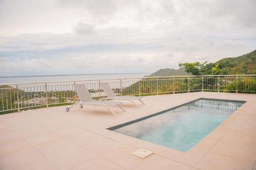 Friar's BayVilla Sunset Heights - La Savane的一个带游泳池和两把椅子的庭院和大海
