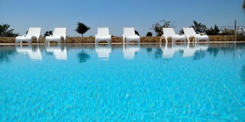 a group of white chairs sitting in a swimming pool at Sea view - Villa Emmanouella in Makry Gialos