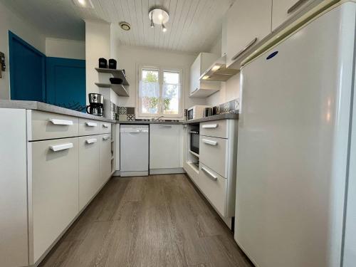 - une cuisine avec des placards blancs et des murs bleus dans l'établissement Maison 3 pièces 5 couchages La Brée Les Bains LBO000-052, à La Brée-les-Bains