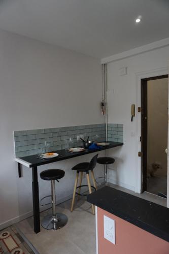 une cuisine avec un comptoir noir et des tabourets de bar dans l'établissement Cosy appartement 4 personnes aux Arceaux - Proche centre ville Montpellier, à Montpellier