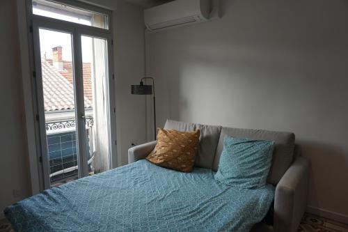 une chambre avec un lit avec des draps bleus et une fenêtre dans l'établissement Cosy appartement 4 personnes aux Arceaux - Proche centre ville Montpellier, à Montpellier