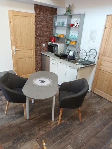 une petite cuisine avec une table et deux chaises dans l'établissement La Clé des Sources, à Fontaine