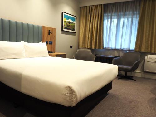 a hotel room with a large bed and a chair at Holiday Inn Telford Ironbridge by IHG in Telford