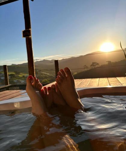 a person laying in a pool with their feet in the water at Chalé Contêiner com Vista para Serra da Canastra in São Roque de Minas