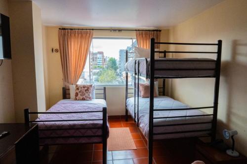 a room with two bunk beds and a window at Hotel Casa Kolping Quito in Quito