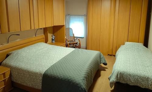 a bedroom with two beds and a chair and a window at Hoeve Hofgaarde in Heers