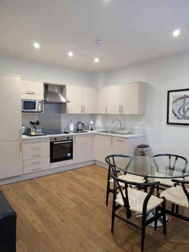 a kitchen with white cabinets and a glass table at House of Fisher - 100 Kings Road in Reading