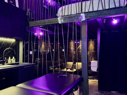 Cette chambre dispose d'un éclairage violet et d'une table avec un lit. dans l'établissement Love Room - Dayan 1, à Villeurbanne