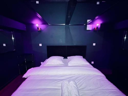 - une chambre avec un lit blanc et des lumières violettes dans l'établissement Love Room - Dayan 1, à Villeurbanne