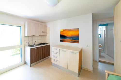 eine Küche mit weißen Schränken und einem Gemälde an der Wand in der Unterkunft Residence Le Orchidee in Vieste