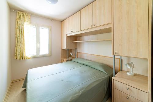Schlafzimmer mit einem Bett, Holzschränken und einem Fenster in der Unterkunft Residence Le Orchidee in Vieste