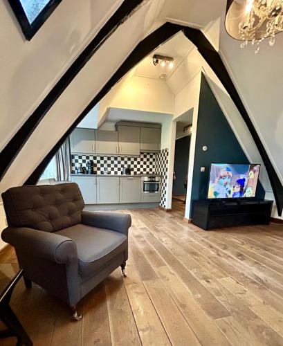 an attic living room with a couch and a tv at Bovenop 19 in Hippolytushoef
