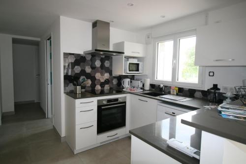 une cuisine avec des armoires blanches et un four à plaques de cuisson dans l'établissement La Tranche centre ville maison neuve avec parking voiture WIFI, à La Tranche-sur-Mer
