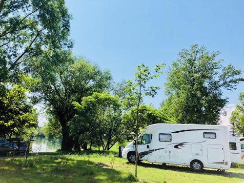 a white caravan parked in a field next to a lake at Camping Bela krajina - Pitches in Gradac