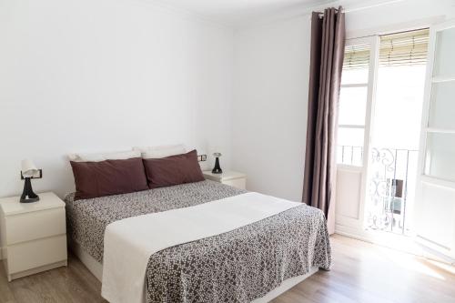 a white bedroom with a bed and a window at Sopranis by Gades Gestión in Cádiz