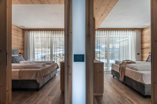 two beds in a room with wooden walls at Arnica Alpin Lodge in Cavedago