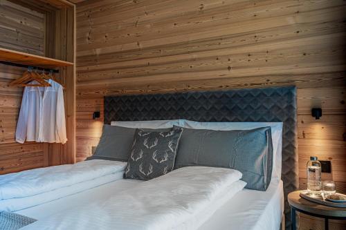 a bedroom with a white bed with a wooden wall at Arnica Alpin Lodge in Cavedago