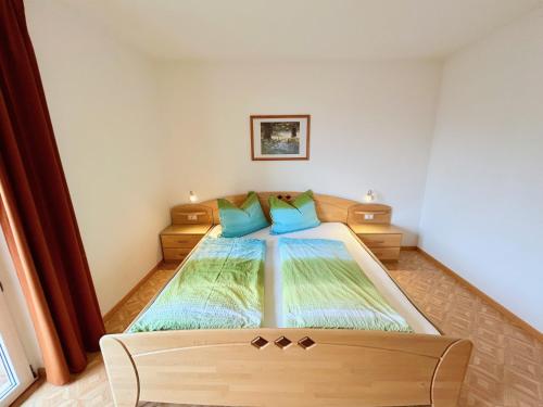 a bedroom with a large bed with blue pillows at FeWo Ortler auf dem Familien- & Tierfreundlichen Haslinger Hof in Saltusio