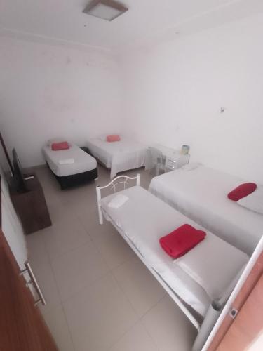 a white room with two beds with red sheets at Pousada Maria Bonita in Macau