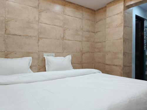 a bed with white sheets and pillows in a room at Hotel Shyama Palace in Jamshedpur