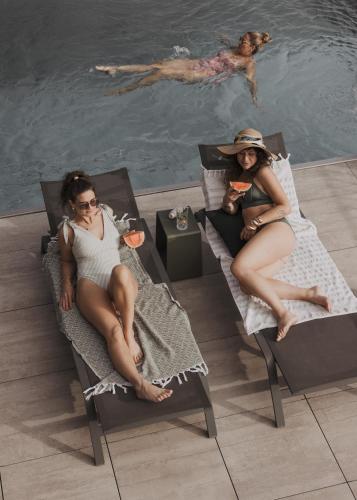 two women sitting in chairs next to a swimming pool at GOING TRIPLE A apartments EAST in Going