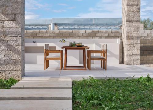 a wooden table and chairs on a patio with the ocean at Noero Villas Lefkada in Lefkada Town