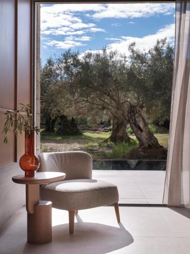 a chair and a table in front of a window at Noero Villas Lefkada in Lefkada Town
