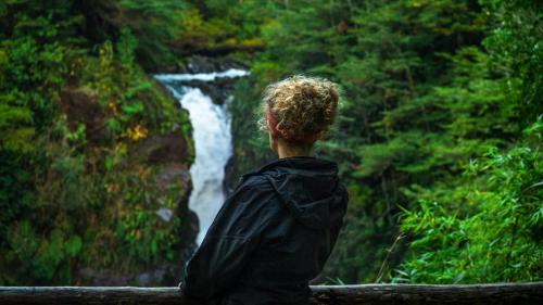 a person standing in front of a waterfall at Centro Turístico Anticura Parque Nacional Puyehue in Anticura