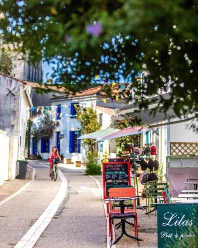 a woman riding a bike down a street with tables and chairs at Camping 3 étoiles - Piscine - ccaihff in Saint-Georges-de-Didonne
