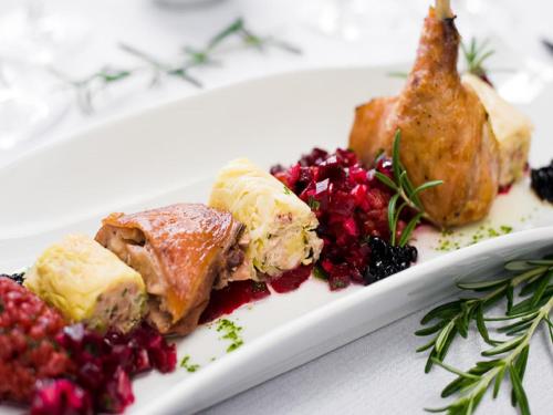 a plate of food with meat and berries on a table at Hotel Constancja in Częstochowa