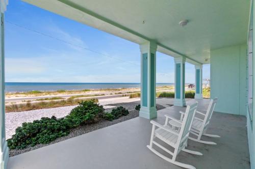 a porch with two white chairs and the ocean at Oceanshore Oasis in Flagler Beach