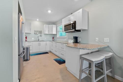 a kitchen with white cabinets and a counter with stools at Oceanshore Oasis in Flagler Beach