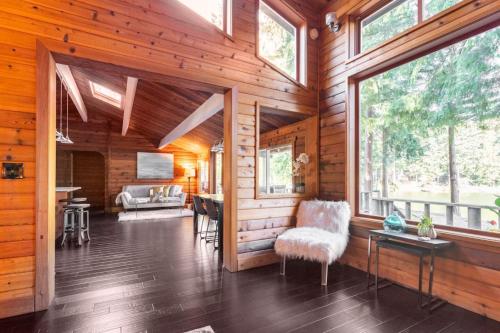 a living room with wooden walls and windows at Charming Lakefront Log Cabin in Fall City