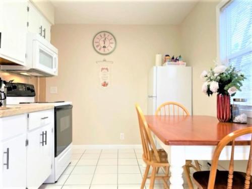 a kitchen with a wooden table and a white refrigerator at Pontiac - Secluded Backyard, Pet Friendly in Fort Wayne