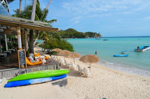a beach with umbrellas and a green boat on it at JP Resort Koh Tao in Koh Tao
