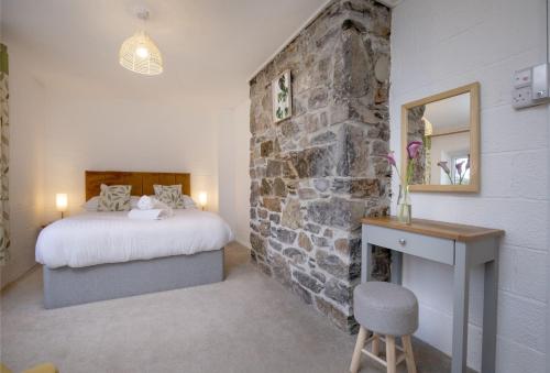 a bedroom with a stone wall with a bed and a desk at Fernwood in Totnes