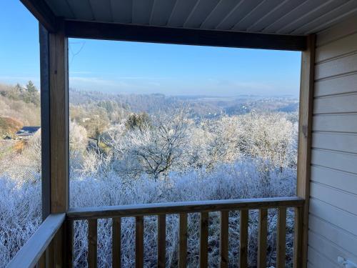 a window of a porch with snow covered trees at Chalet Bouillon - Parc de vacances Papillon Bouillon in Bouillon