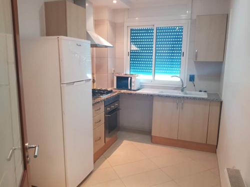 a kitchen with a white refrigerator and a window at Lovely apartment near Tunis Mall - Lac2 Tunis in Tunis