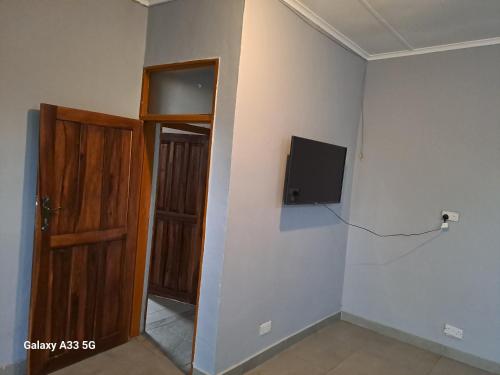 a room with a door and a tv on the wall at The Little Cave in Livingstone