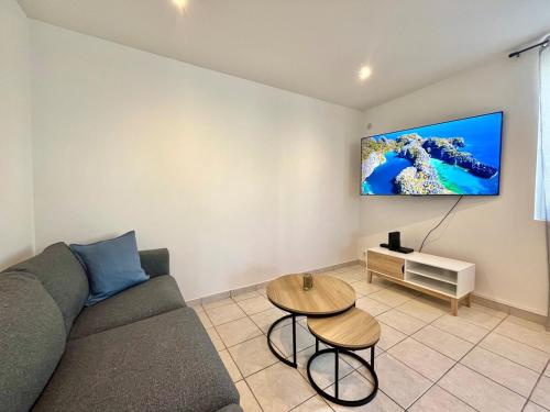 a living room with a couch and a tv on the wall at Maison de ville rénovée à 15 min de Lyon in Pierre-Bénite