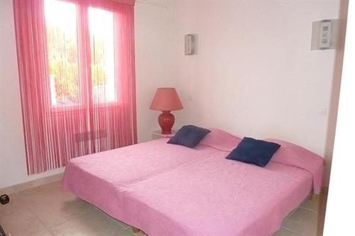 - une chambre avec un lit rose, une lampe et une fenêtre dans l'établissement Maison 4 pièces 6 couchages Saint Pierre d'Oléron SPO000-691, à Saint-Pierre-dʼOléron