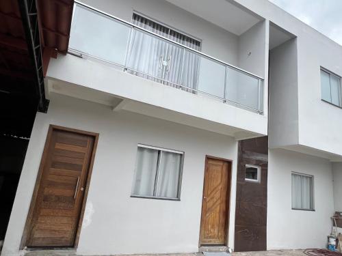 a white house with two doors and a balcony at Quarto com banheiro privado em casa de família 15km de Belém in Ananindeua