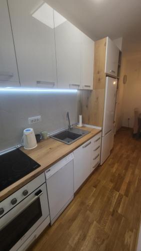 a kitchen with white cabinets and a sink and a refrigerator at Konatar Apartmants in Kruševac