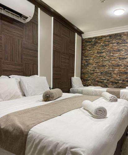 two beds in a bedroom with a brick wall at Mass Paradise Hotel in Aqaba