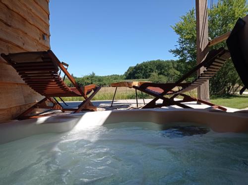 - un bain à remous avec deux chaises et une table dans l'établissement Le bain de campagne, à Montereau