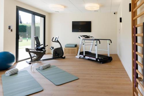 a gym with treadmills and exercise equipment in a room at Les Boréales - Appart'hotel & Restaurant in Villers-sur-Mer