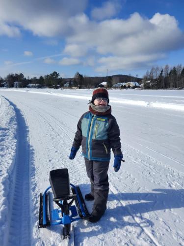 a young child standing on a sled in the snow at Chalet Mathis in Saint-Raymond