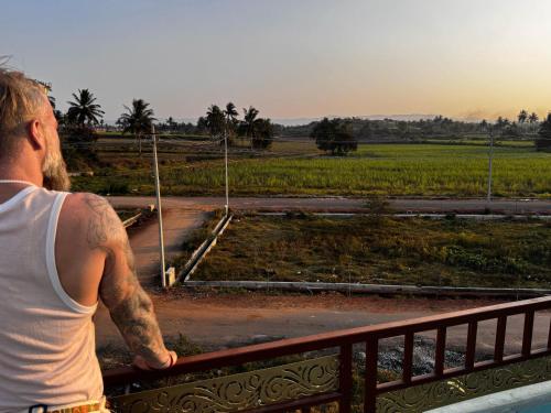 a man standing on a fence looking at a field at Budha Home Stay in Hampi